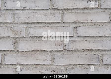 White brick wall covered with limewash. Textured background of old brick, close-up, for design, renovation, and decorative purposes. Stock Photo