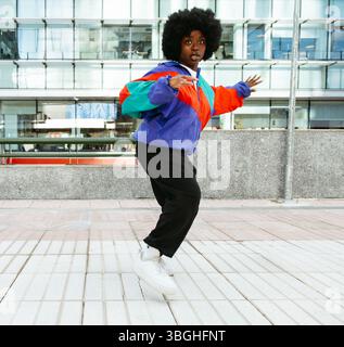 Young afro woman dancing with joy in the city street Stock Photo