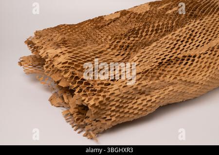 Sand-colored honeycomb-shaped packaging paper for gentle transport of fragile items, set against a textured white background. Stock Photo