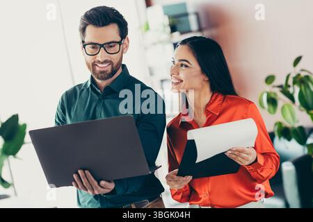Two colleagues discussing ideas and documents in a modern office environment with teamwork and professional collaboration. Stock Photo
