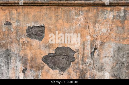 Damaged old plaster wall with cracks, peeling paint, exposed concrete and weathered texture. Suitable for backgrounds, decay, architecture design. Stock Photo