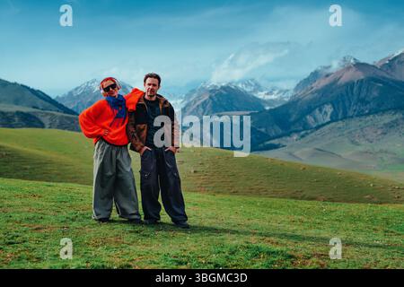 Man and woman tourists standing in the mountains on green meadow Stock Photo