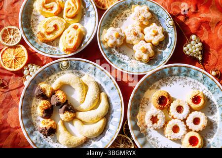Various Christmas cookies, served on individual plates on a red Christmas tablecloth Stock Photo