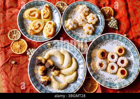 Various Christmas cookies, served on individual plates on a red Christmas tablecloth Stock Photo