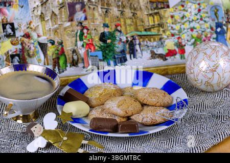 Orange cookies with chocolate confectionery on a plate and cup of coffee, arranged with a golden angel figurine, silver stars, Christmas bauble and Advent calendar Stock Photo