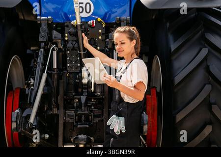 Female technician working with agricultural machinery and using digital tablet. Stock Photo