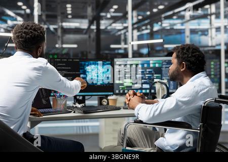 Server room manager and employee in wheelchair use artificial intelligence to perform computing tasks. Data center team leader and engineer with disability use AI for machine learning workloads Stock Photo