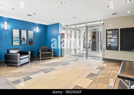 Large room with a blue wall and a black chair. The room is empty and has a modern feel Stock Photo