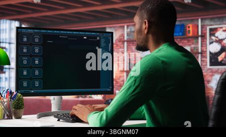 Black male freelancer at home uses AI chatbot for task completion, automation and machine learning. Young adult uses artificial intelligence to generate new ideas with prompts. Camera A. Stock Photo