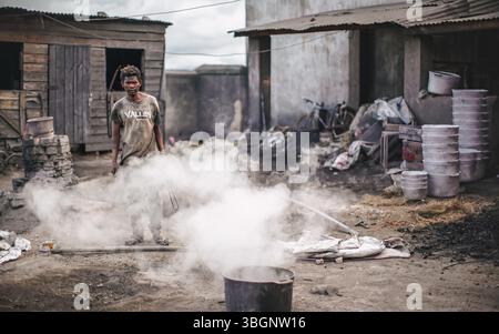 Ambatolampy, Madagascar - April 25, 2019: Aluminium processing factory, cans are melting down in pots with boiling water over fire outside, steam abov Stock Photo