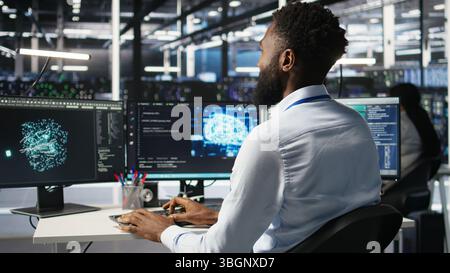 Server hub engineering team interprets AI generated data analytics graphs. Teamworking data center colleagues using artificial intelligence program showing predictive system metrics, camera A Stock Photo