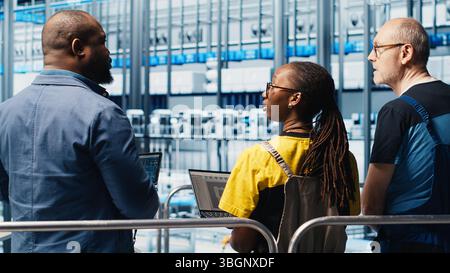 Manager supervising photovoltaic smart factory workers designing production lines in CAD software. Industry 4.0 solar panels plant team leader overseeing employees optimizing floor layouts, camera A Stock Photo