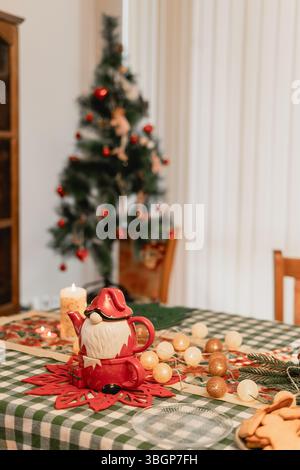 Warm cozy Christmas atmosphere with a Santa teapot and candlelit table full of festive details including garlands pine branches cookies and a tree Stock Photo