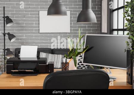 Modern printer with plant and computer monitor on desk in office Stock Photo