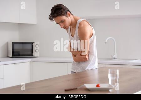 Young man with anorexia refusing from food in kitchen Stock Photo