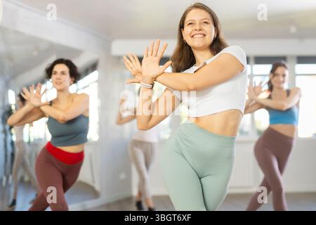 Cheerful young female instructor leading Zumba class for women Stock Photo