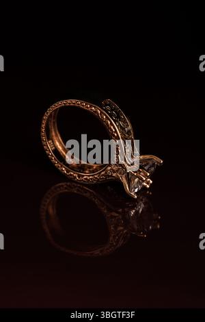 Luxe jewelry close-up featuring golden ring with diamonds in sharp focus and moody shadows – romantic, elegant, symbolic and modern. Stock Photo