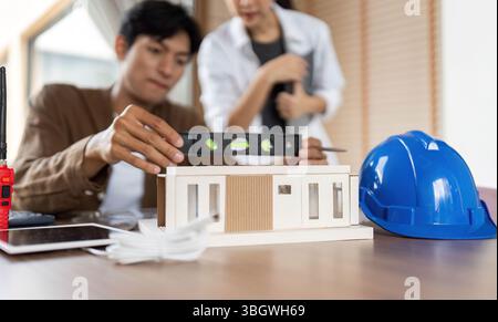 ESG in Architecture. Professionals collaborating on sustainable building design with a model. Stock Photo