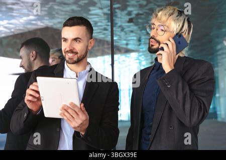 Businessmen working together with tablet and phone in modern glass office Stock Photo