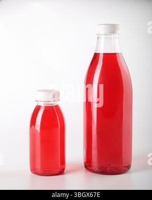 A collection of glass bottles filled with a vibrant red liquid set against a gray background Stock Photo