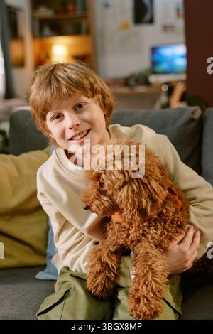 Portrait of Caucasian Child Boy Smiling While Holding Puppy at Home Stock Photo