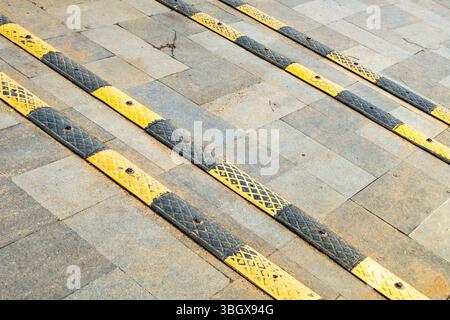 Row of yellow and black barriers are on a gray tile floor. The barriers are placed in a row, with the yellow and black stripes alternating Stock Photo