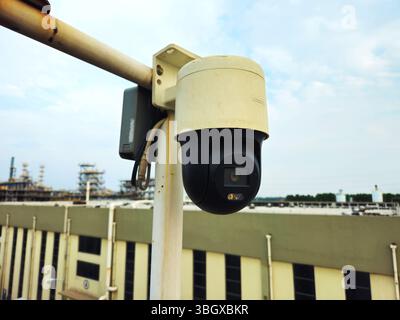 Security Camera Overlooking Chinese Industrial Plant - PTZ Dome on Pole Stock Photo
