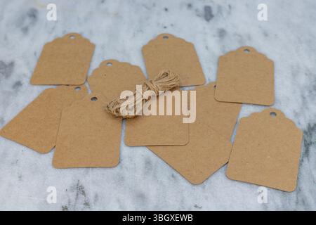 Scattered Kraft Paper Gift Tags with Twine on Marble Surface Stock Photo