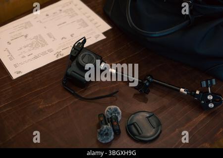 A setup for a vlogger or content creator, featuring a compact camera on a mount with external microphones, laid out on a wooden table. Stock Photo