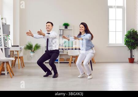 Businessman, businesswoman doing fitness, yoga at workplace in squat pose, happy meditating  Stock Photo