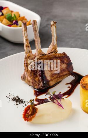 Grilled lamb chops with mashed potato, polenta cake and garnish Stock Photo