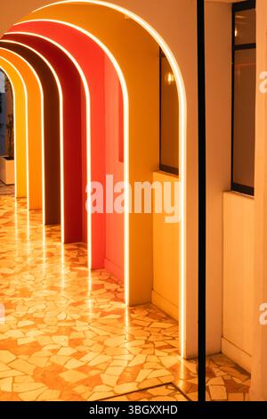 A stunning architectural perspective down a hallway of repeating, colorful arches, each illuminated with a vibrant glow, creating a modern and futuris Stock Photo