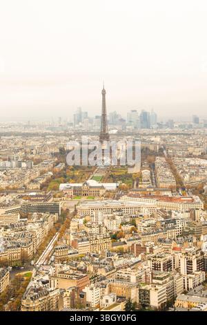 An aerial view of Paris on a hazy day, with the iconic tower as the central focal point, surrounded by sprawling city blocks, parks with autumn foliag Stock Photo