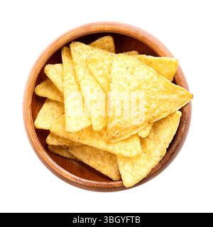 Tortilla chips in a wooden bowl. Classic, crunchy snack food, made from corn tortillas, cut into triangle shaped wedges, fried in oil, slightly salted. Stock Photo