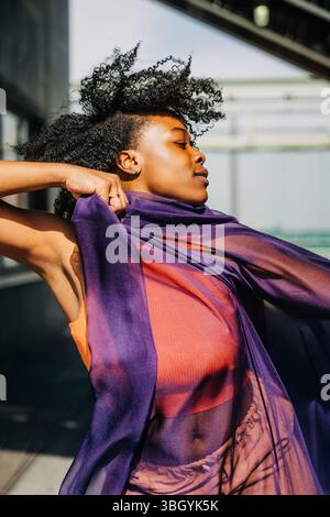 Close-up of woman wrapped in purple fabric with windswept hair Stock Photo