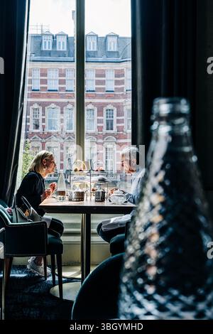 Couple enjoying afternoon tea by window in elegant setting Stock Photo