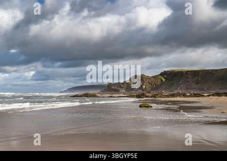 Storm clouds over deserted beach Northcott Mouth Cornwall early morning in June Stock Photo