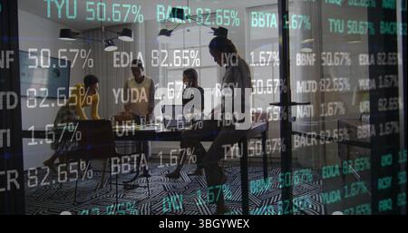 Collaborating professionals in business attire around table at office, with laptops and notebooks Stock Photo