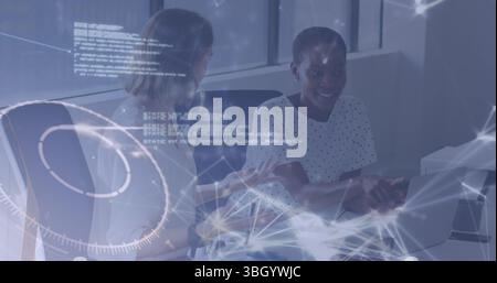 Collaborating mid adult women debugging code at office desk, with laptops and network graphics Stock Photo