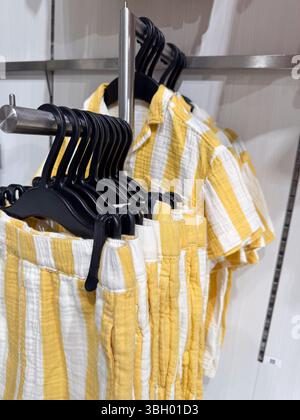 Yellow and white striped clothing displayed on hangers in a retail setting. The image highlights the neat arrangement of the clothes, emphasizing Stock Photo