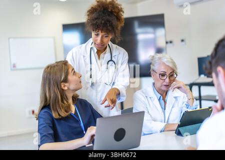 Doctors and nurses collaborating on patient care, analyzing medical data on laptop and tablet, improving healthcare strategies Stock Photo