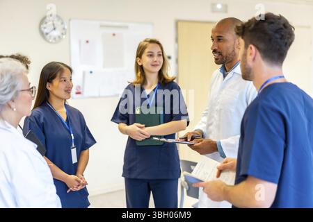 Diverse medical professionals collaborating, sharing expertise, and reviewing patient information during a productive meeting in a hospital setting Stock Photo