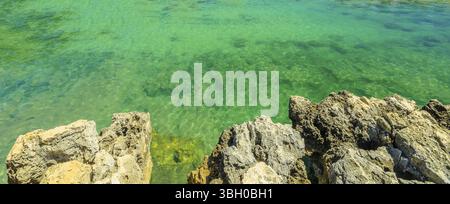 Background texture of coastline reef with cliffs in Portugal with clear green clear water. Copy space. Horizontal panorama Stock Photo