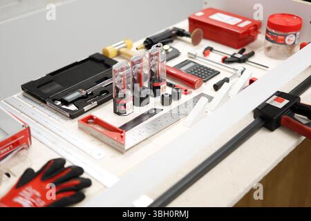 A neatly arranged set of precision workshop tools including clamps, calipers, square rulers, drill bits, and a calculator on a clean work surface Stock Photo