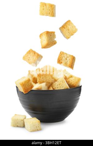 Delicious crispy croutons falling into bowl on white background Stock Photo
