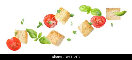 Delicious crispy croutons, tomatoes and herbs flying on white background Stock Photo