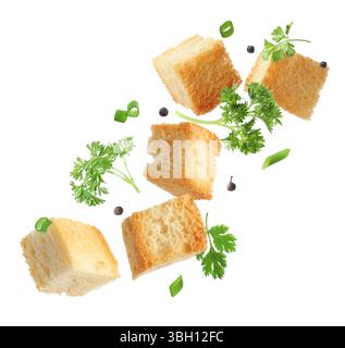Delicious crispy croutons, peppercorns and herbs flying on white background Stock Photo