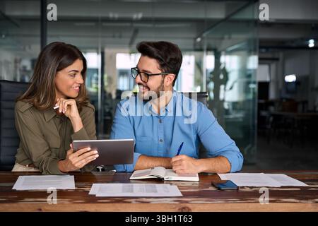 Two happy busy business people talking using digital tablet in office. Stock Photo