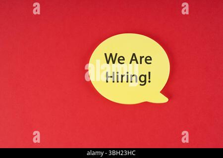 Yellow speech bubble with "We Are Hiring!" text on a red background. Concept image for job vacancies, recruitment, or employment opportunities. Bold a Stock Photo