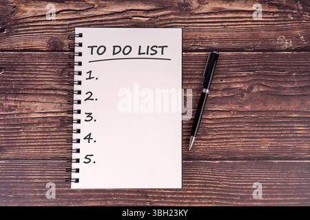 Top view of a blank to-do list in a spiral notebook with a pen on rustic wooden table. Perfect for productivity, planning, organization, or motivation Stock Photo